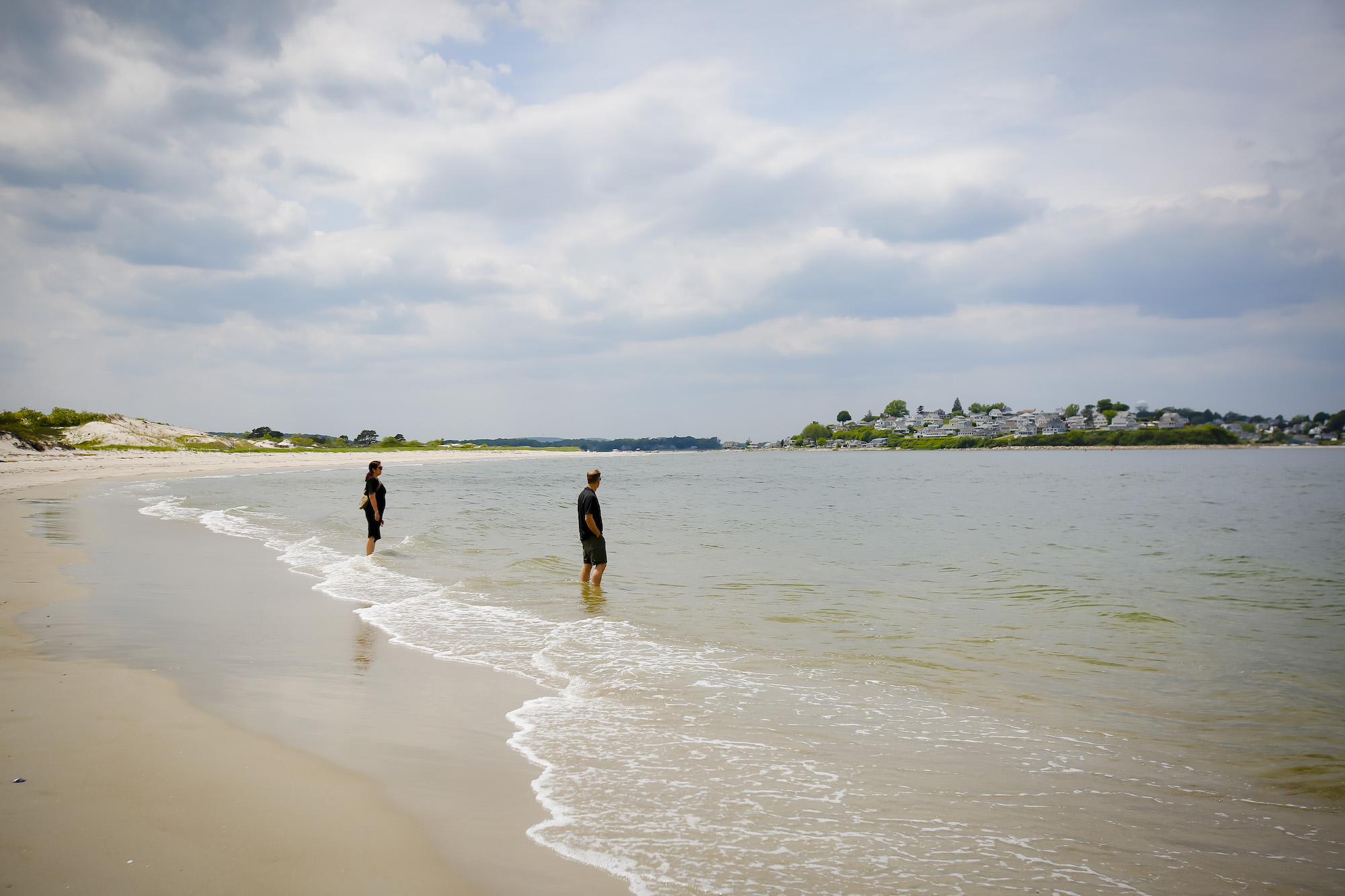 Two people stand in the surf on Crane Beach in Ipswich